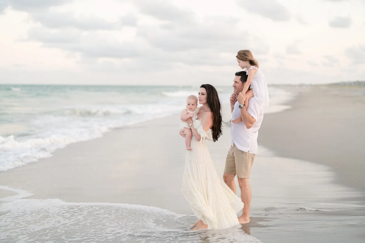Mother with her baby walking the shoreline beside dad in Garden City Beach SC