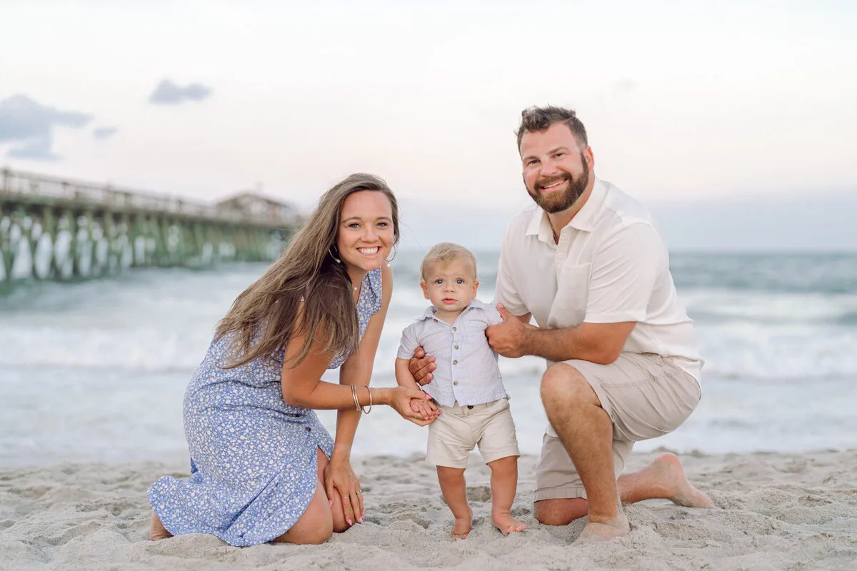 Parents kneeling with their toddler by the pier in Garden City Beach SC