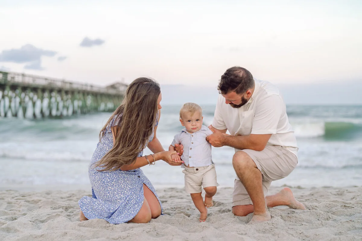 Parents kneeling with their toddler near the pier in Garden City Beach SC