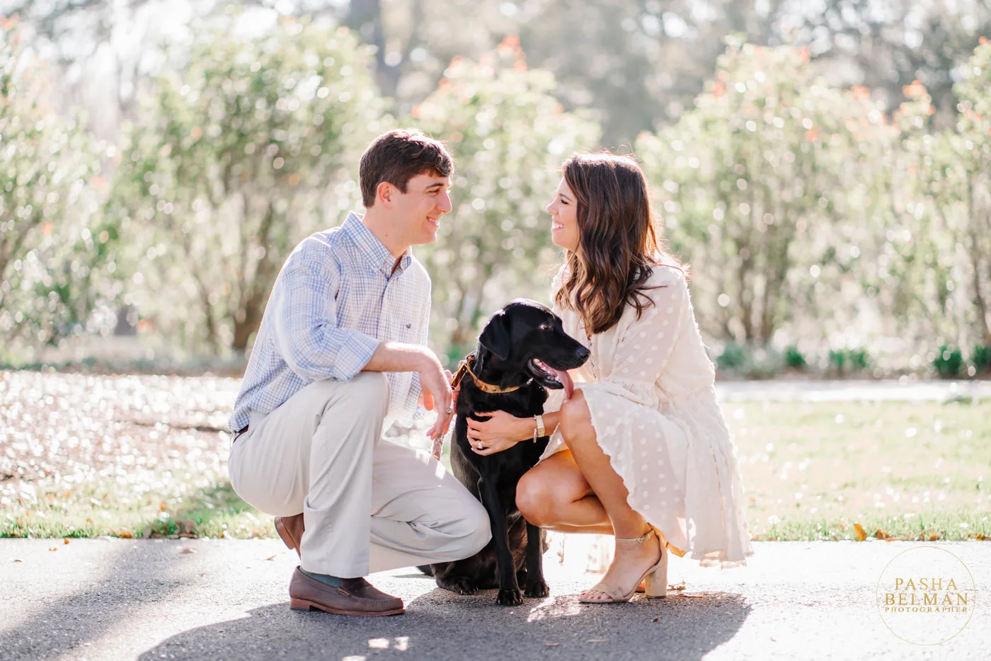 Engaged couple crouching with their black lab on the path at Caledonia Golf and Fish Club in Pawleys Island