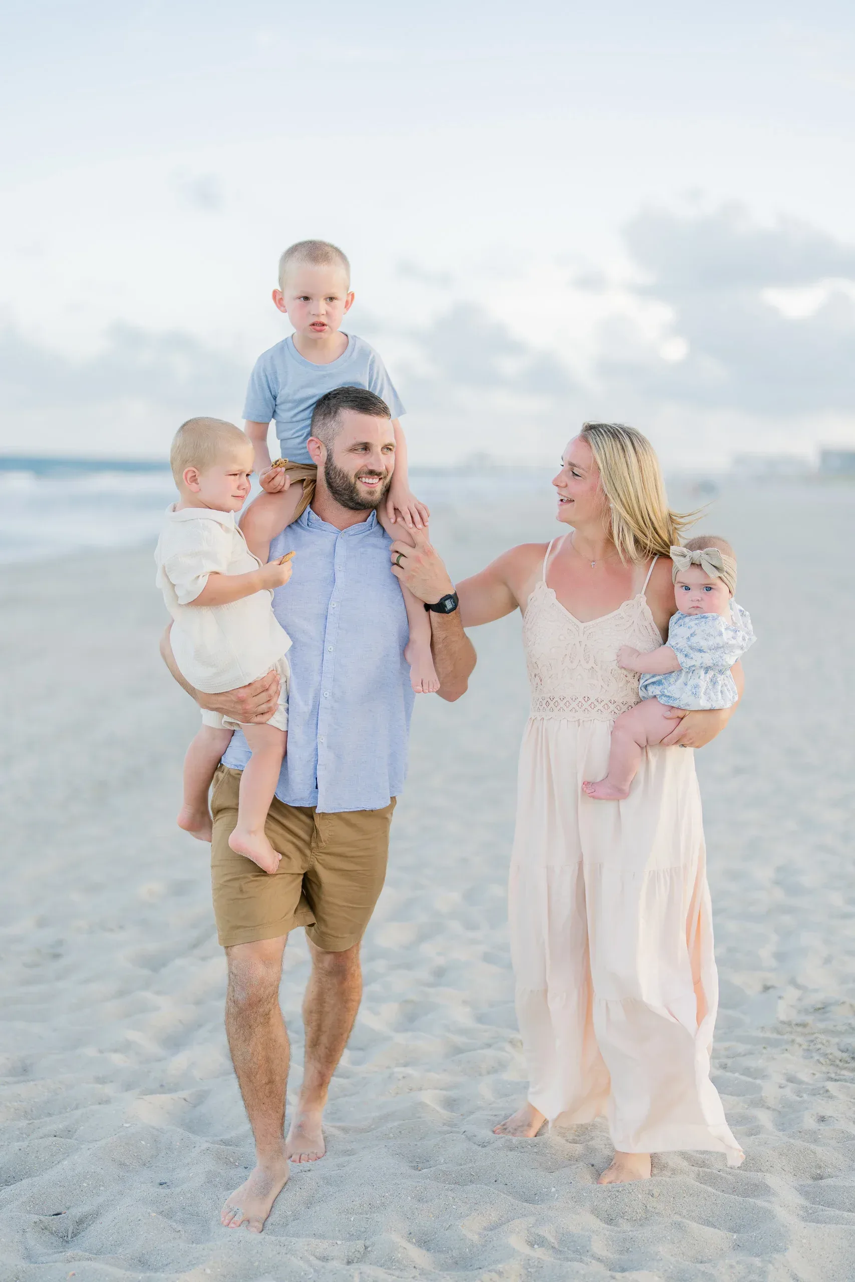 Parents carrying their young children on the beach by Pasha Belman Photography