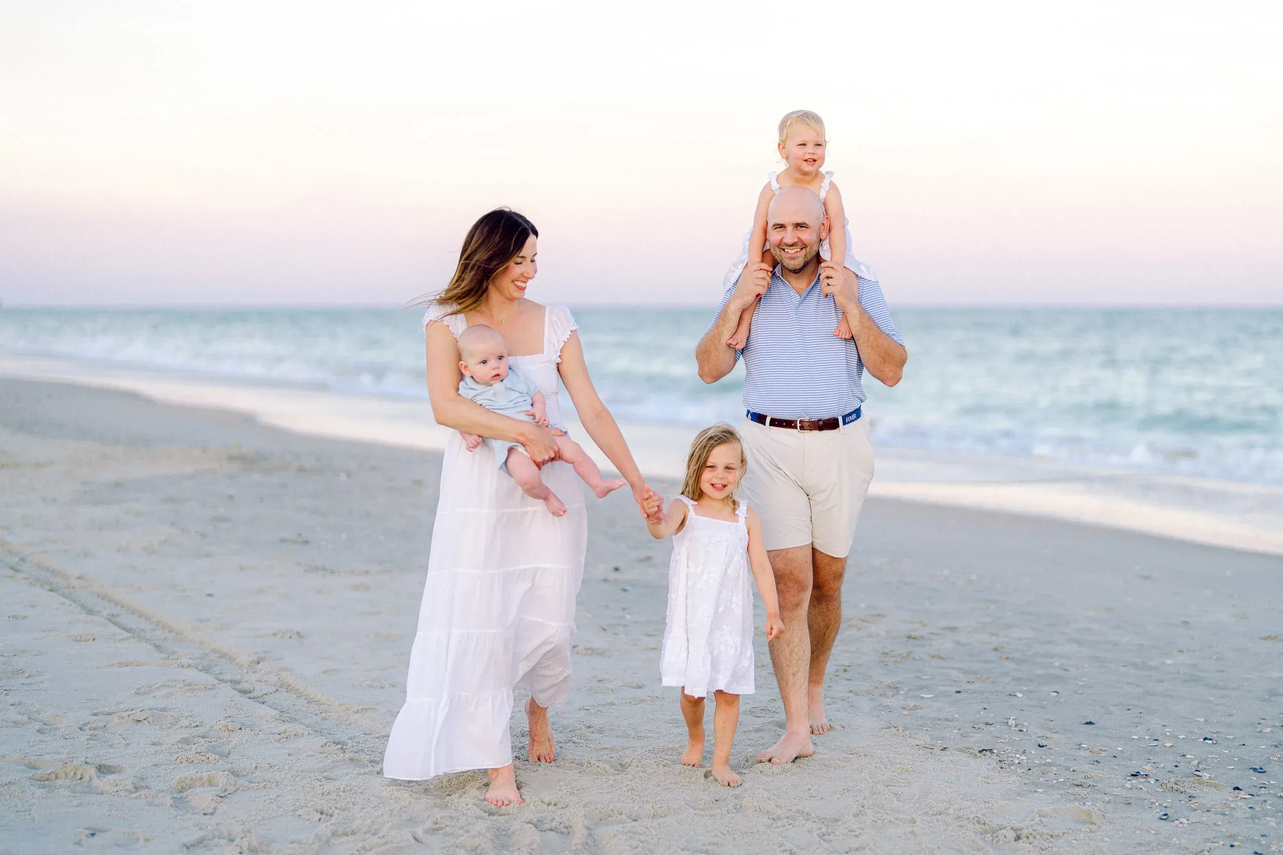 Family walking the beach with their daughters at sunset by Pasha Belman Photography