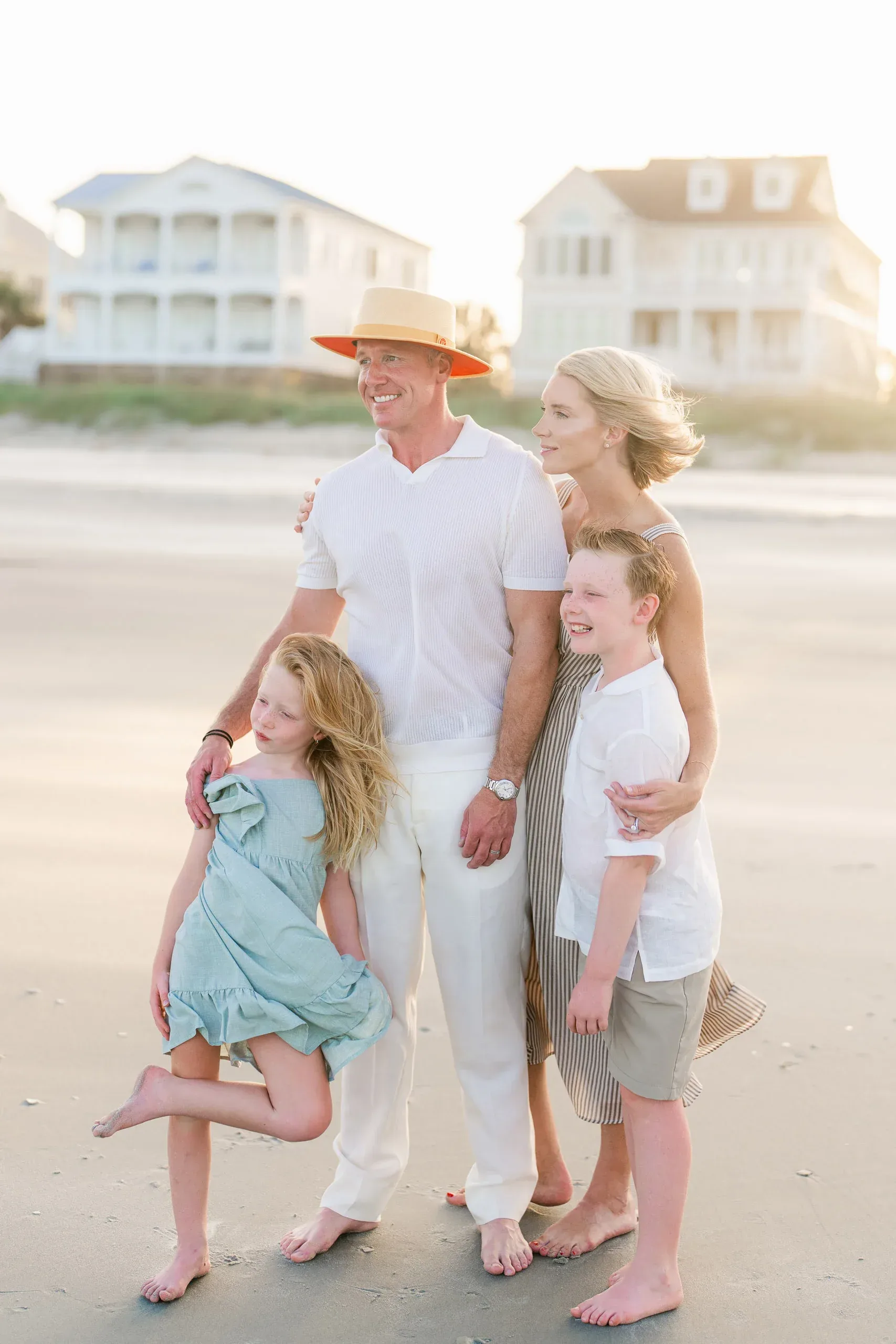 Family with their children on the beach in front of oceanfront homes by Pasha Belman Photography
