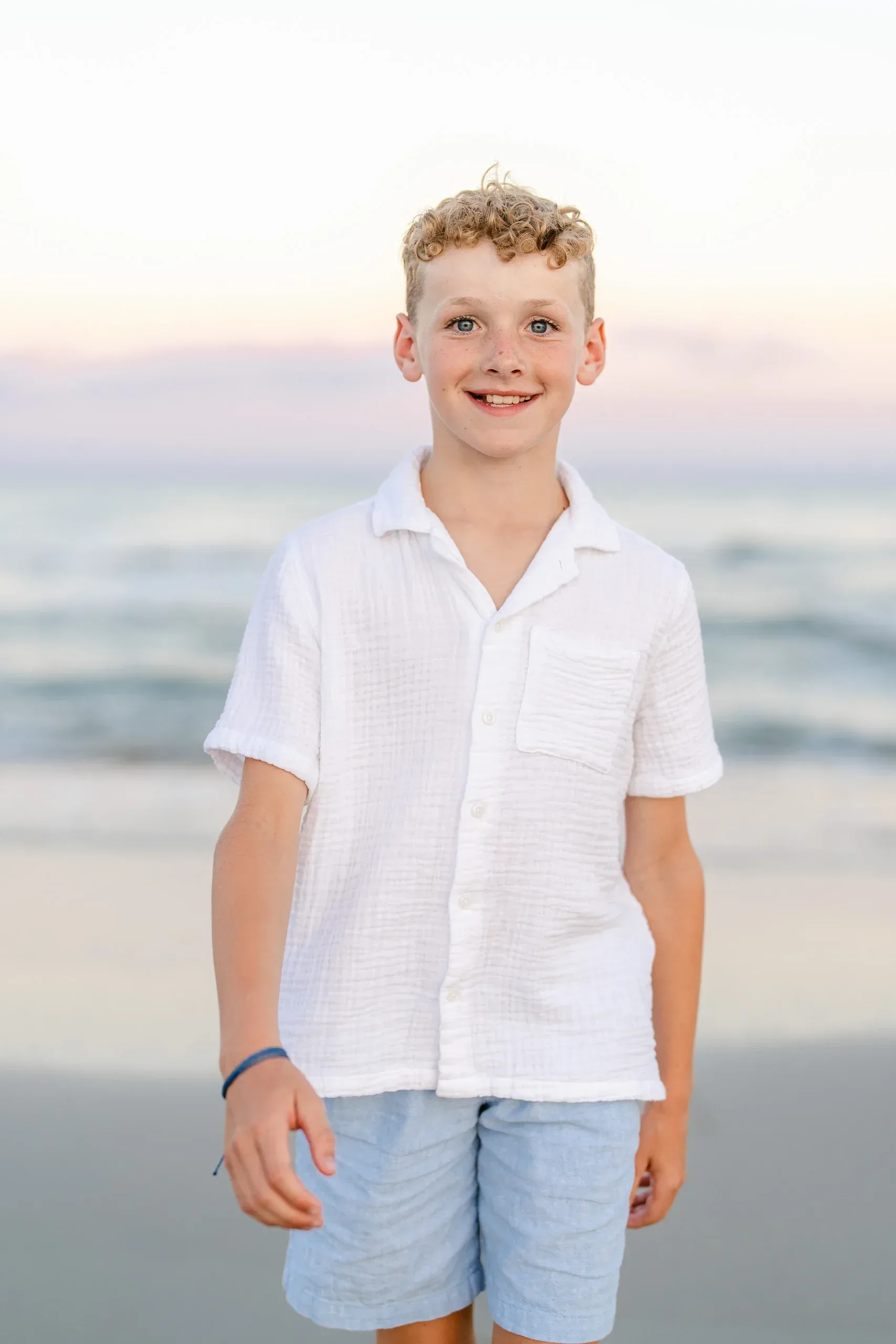 Boy smiling on the beach at sunset by Pasha Belman Photography