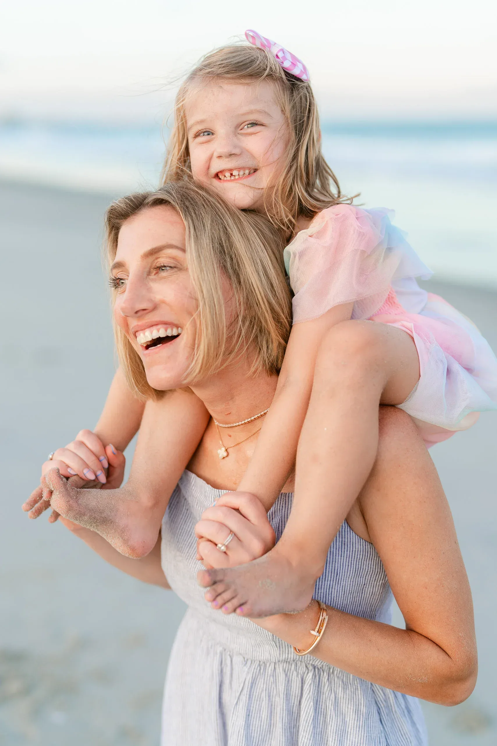 Daughter laughing on her mother's shoulders by Pasha Belman Photography