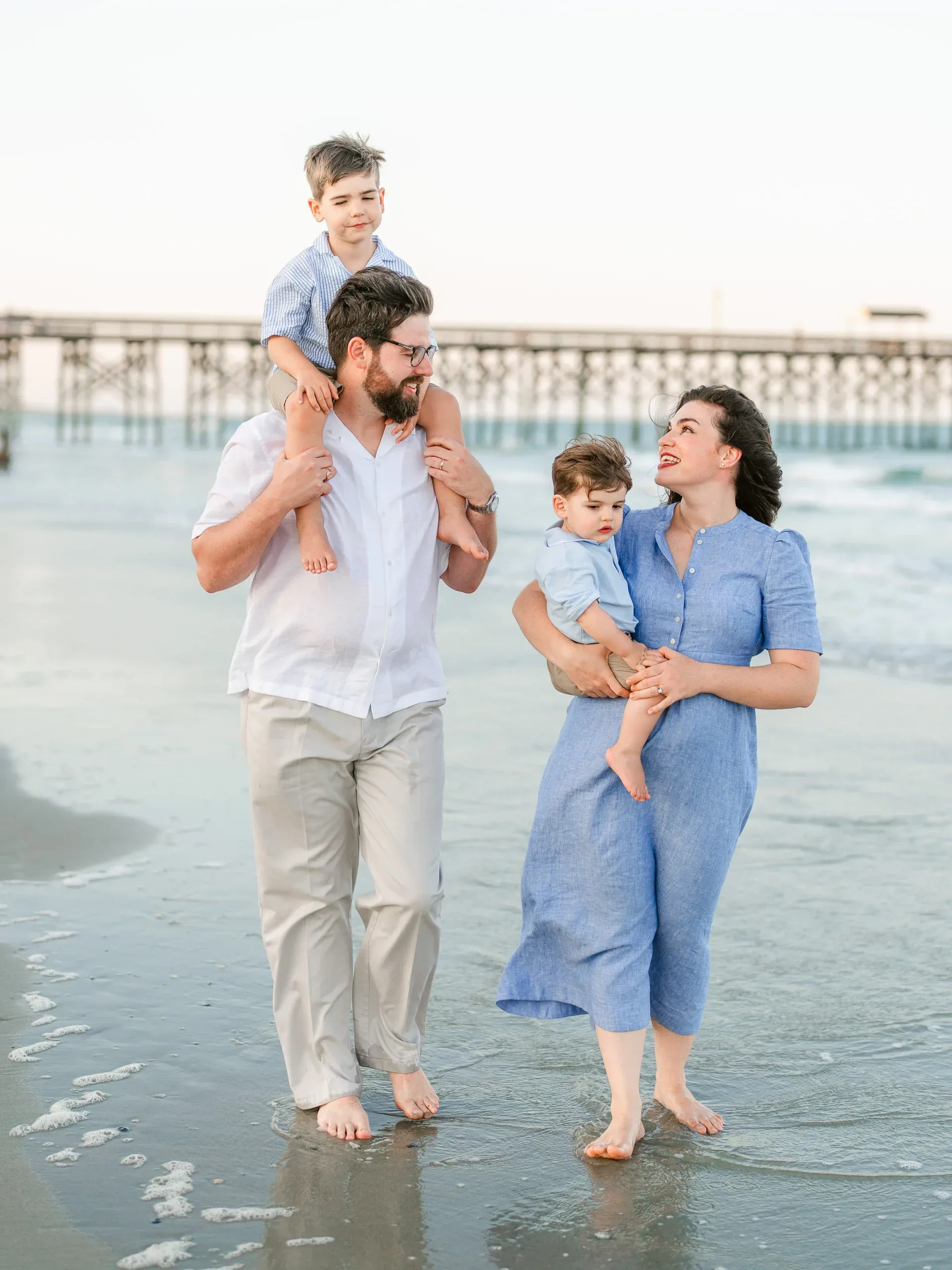 Family on the beach with a child on dad's shoulders by Pasha Belman Photography