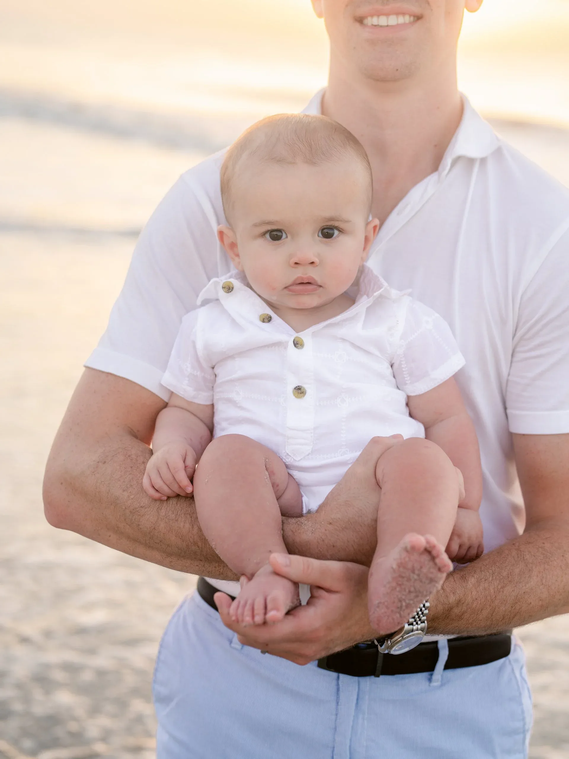 Father holding his baby son by the dunes by Pasha Belman Photography