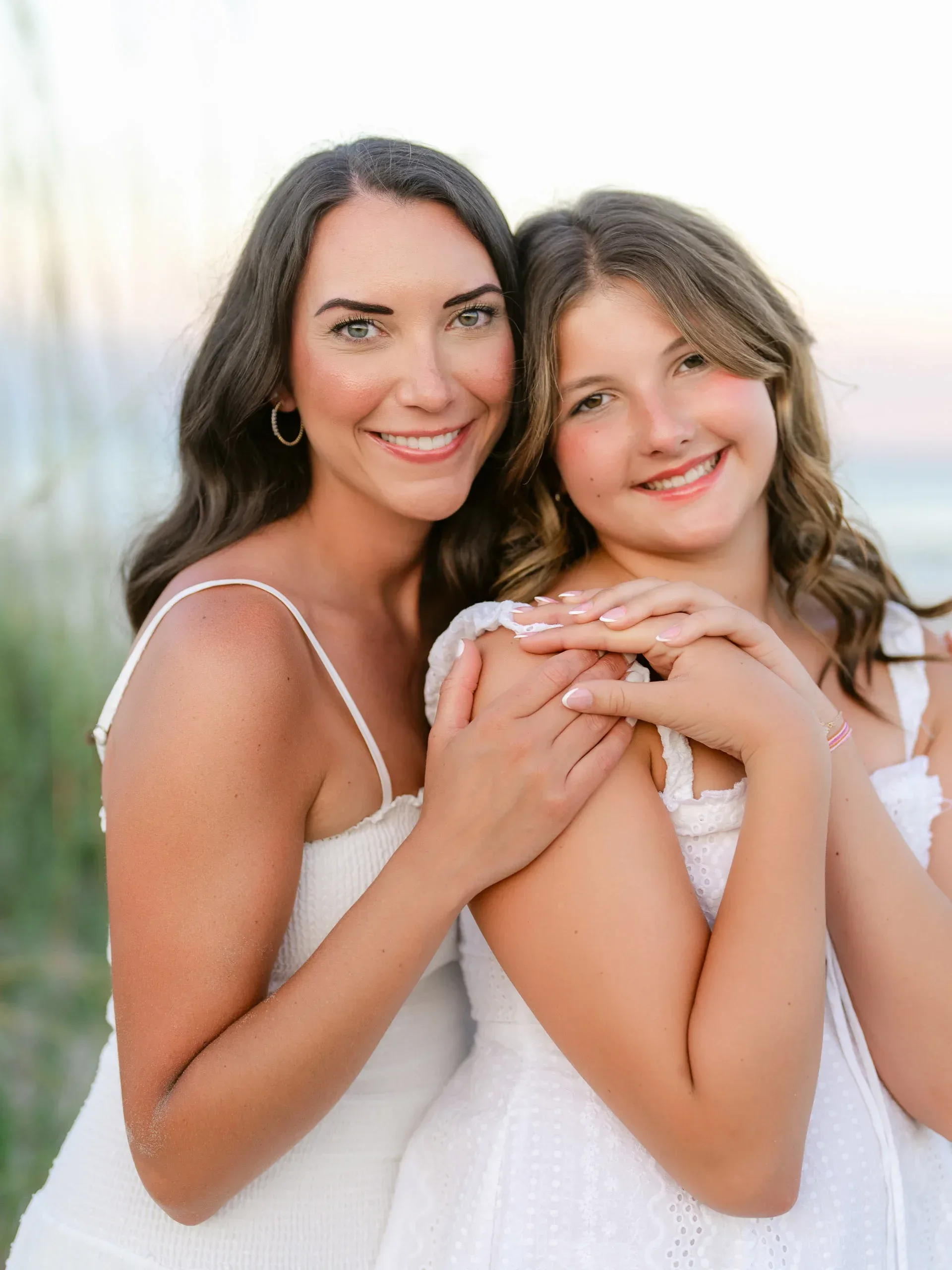 Mother and teenage daughter embracing on the beach by Pasha Belman Photography