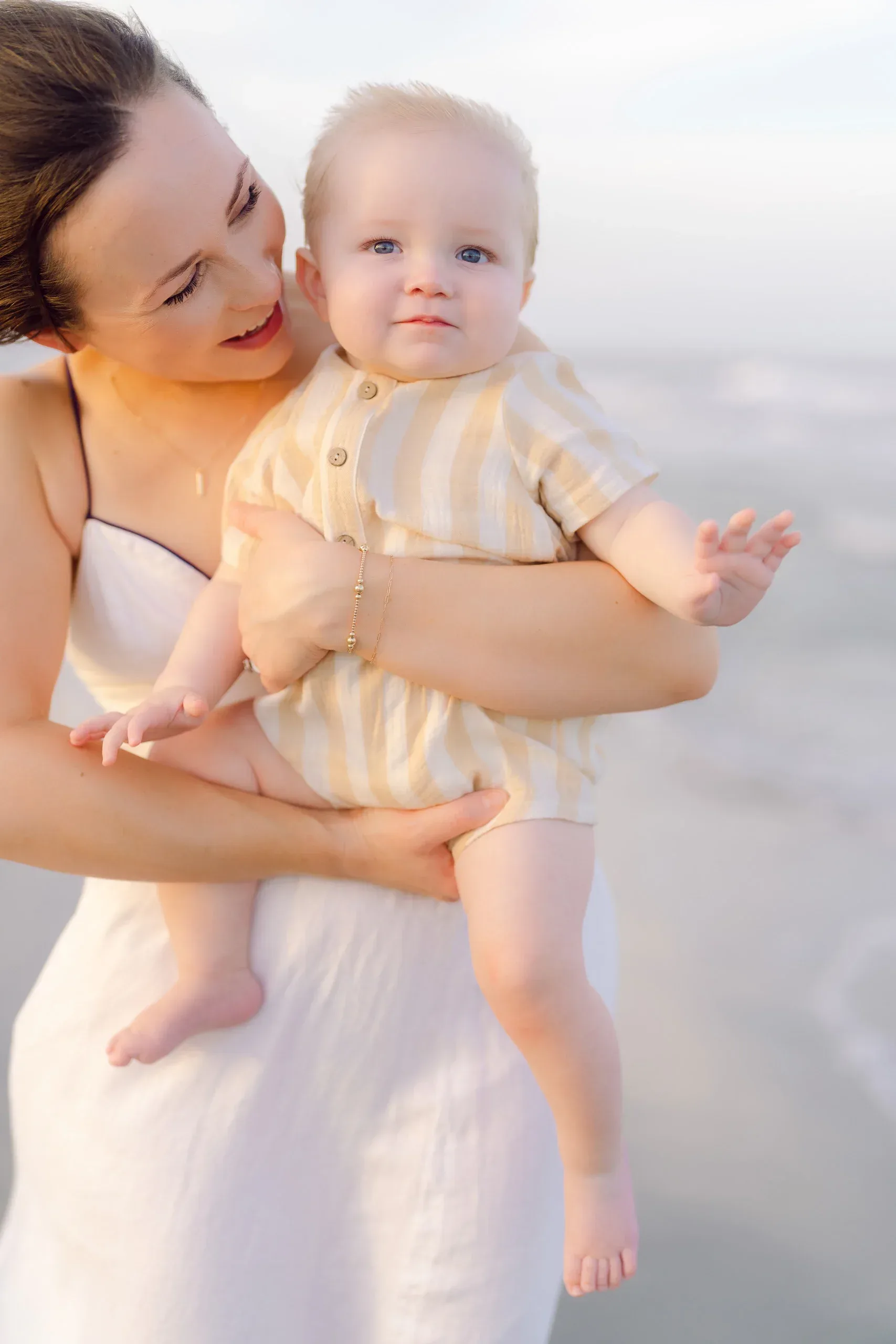 Mother holding her baby boy on the beach by Pasha Belman Photography