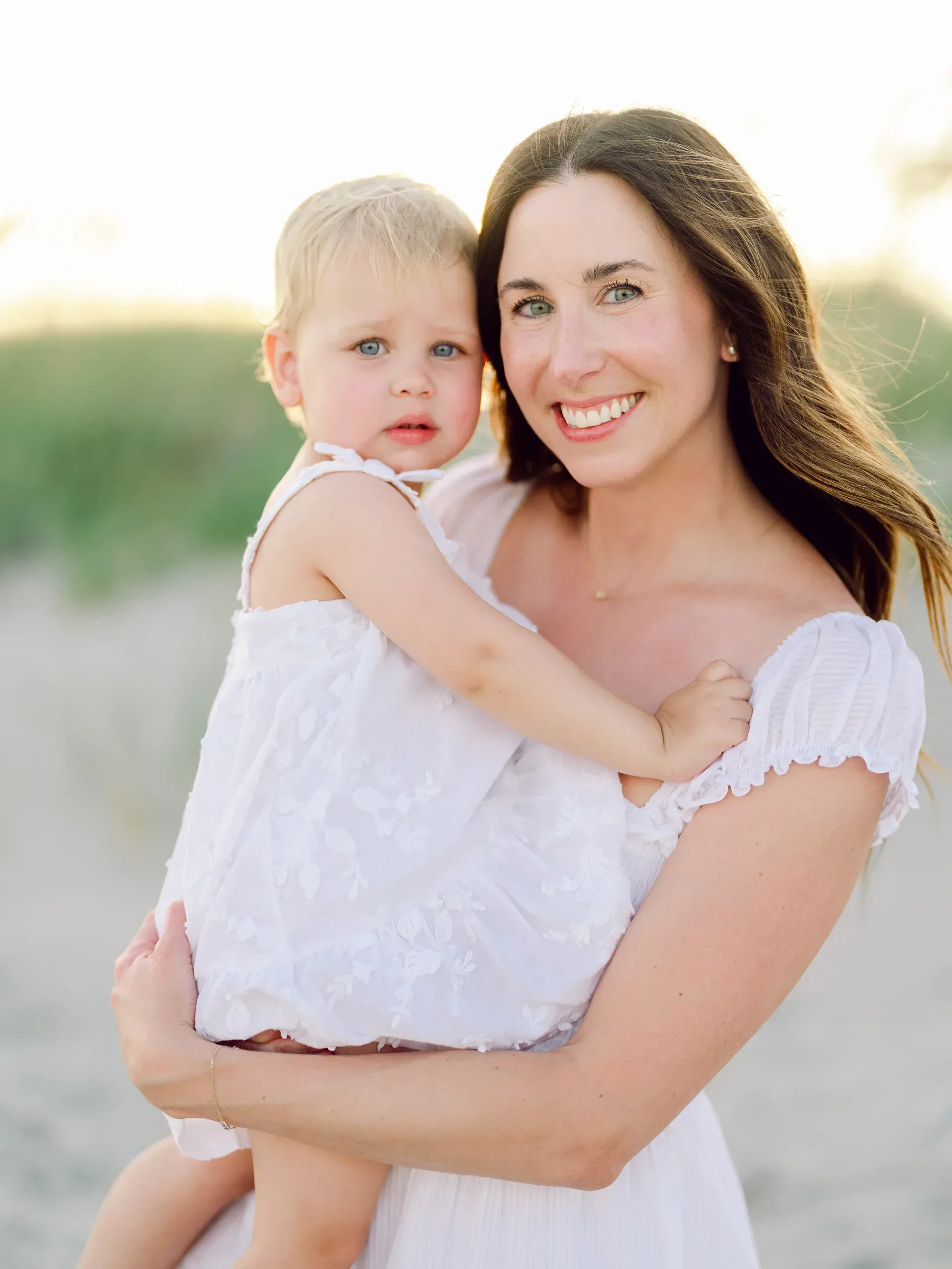 Mother holding her toddler on the beach by Pasha Belman Photography