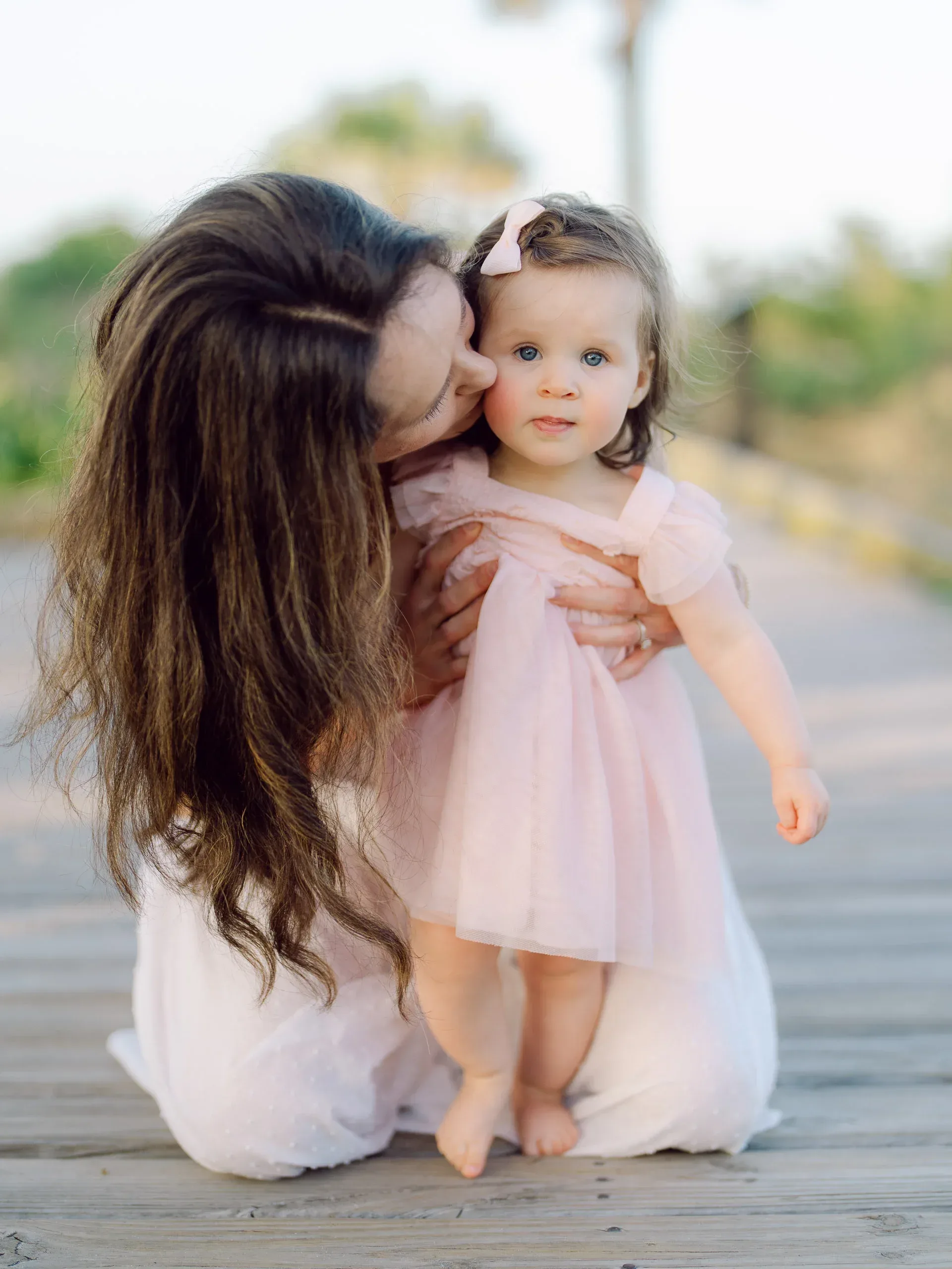 Mother kissing her toddler daughter by the dunes by Pasha Belman Photography