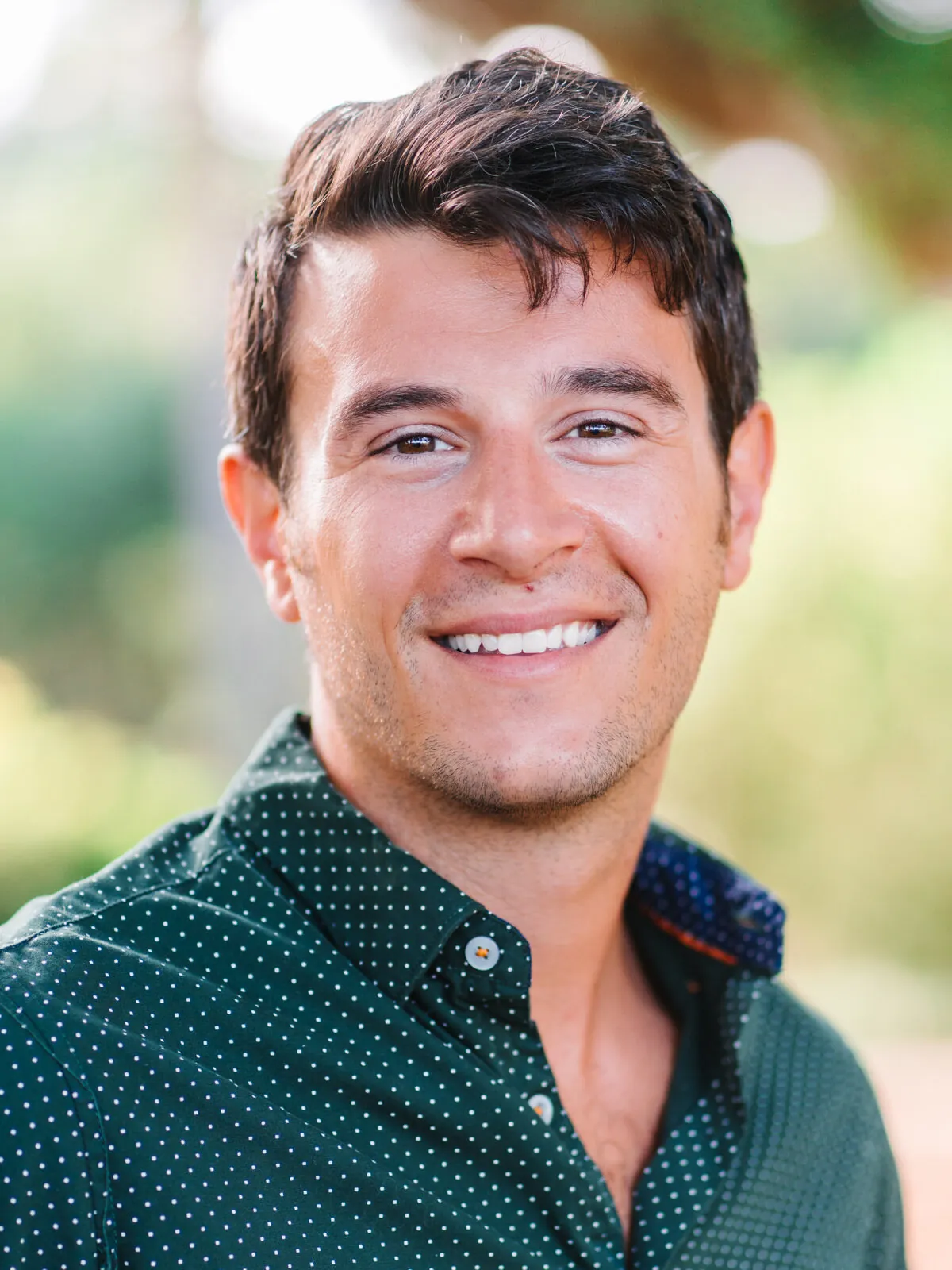 Professional headshot of a smiling man with short dark hair in a green polka-dot shirt, outdoors by Myrtle Beach headshot photographer Pasha Belman
