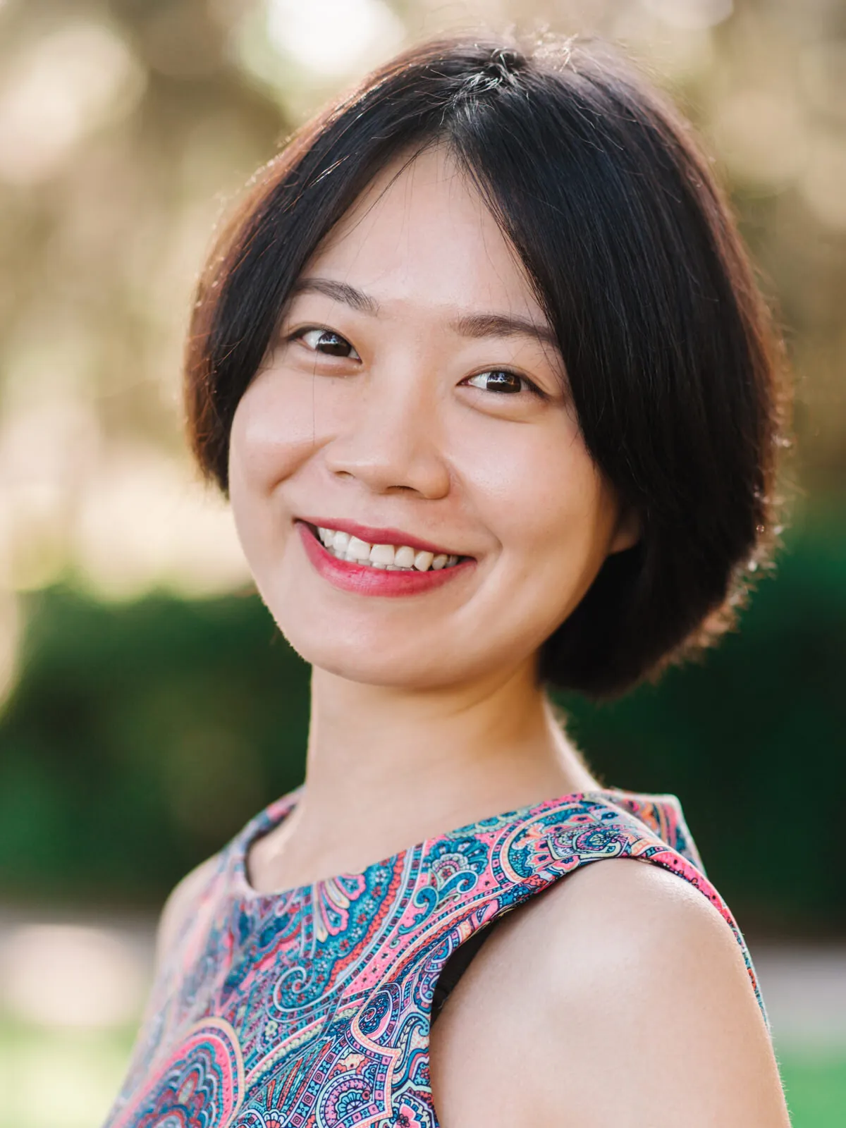 Professional headshot of a smiling woman with a short dark bob in a blue and orange paisley top by Myrtle Beach headshot photographer Pasha Belman