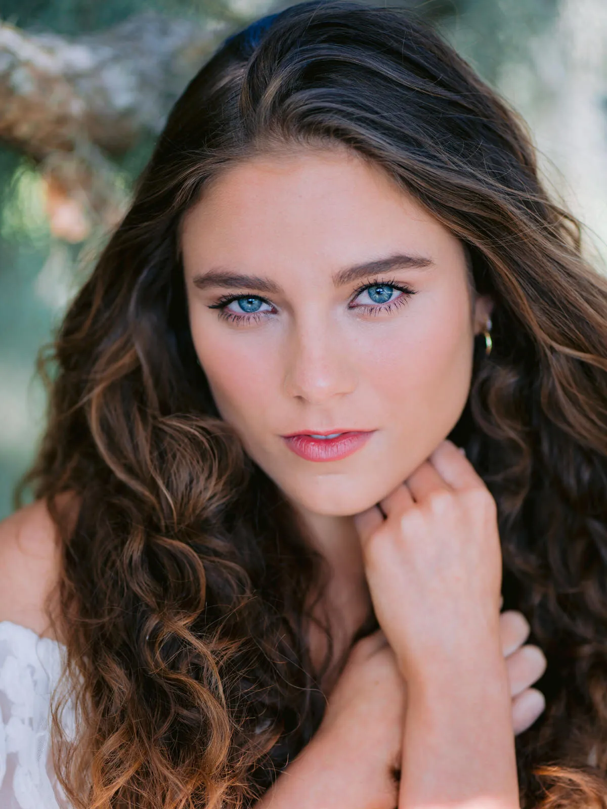Professional headshot of a young woman with long dark curly hair and her hand at her chin by Myrtle Beach headshot photographer Pasha Belman