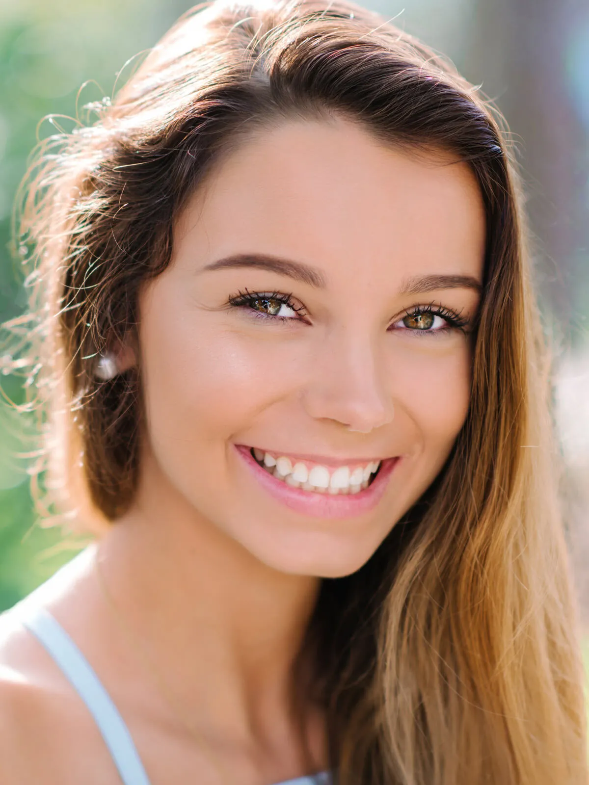Professional headshot of a close portrait of a young woman with long brown hair and a bright smile by Myrtle Beach headshot photographer Pasha Belman
