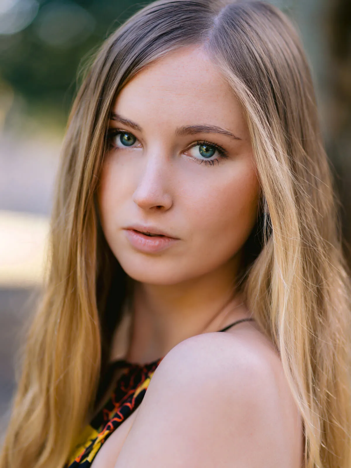 Professional headshot of a young woman with long light brown hair looking toward the camera over her shoulder by Myrtle Beach headshot photographer Pasha Belman
