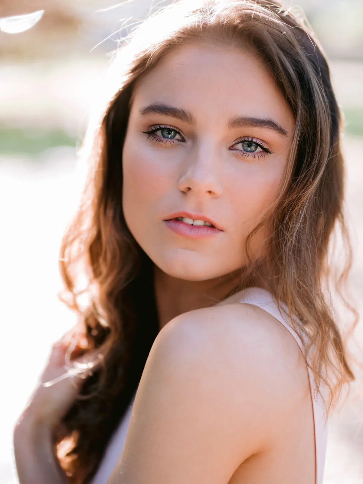 Professional headshot of a young woman with long wavy brown hair looking softly at the camera by Myrtle Beach headshot photographer Pasha Belman
