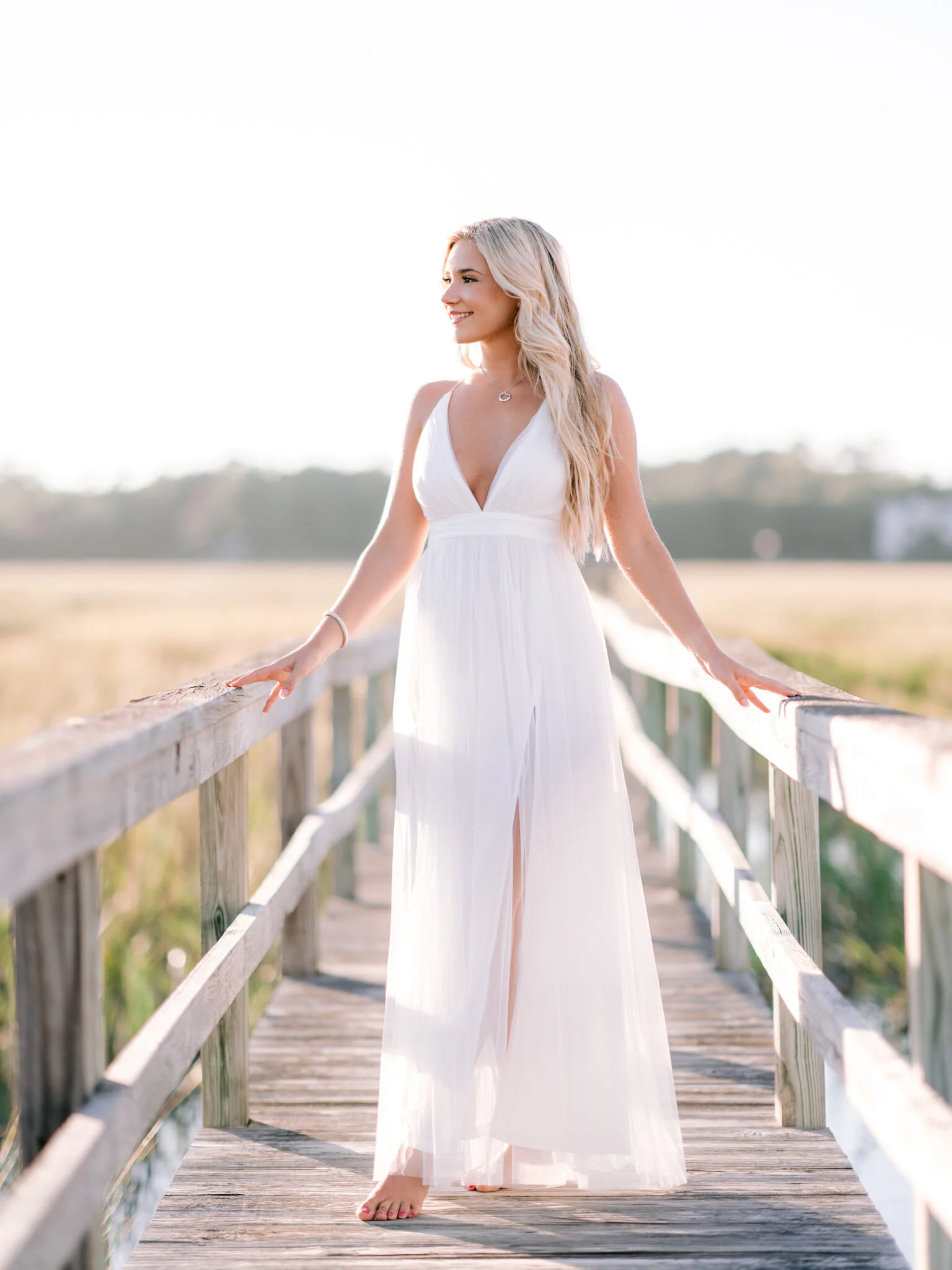 Senior on a marsh boardwalk in a white jumpsuit near Myrtle Beach