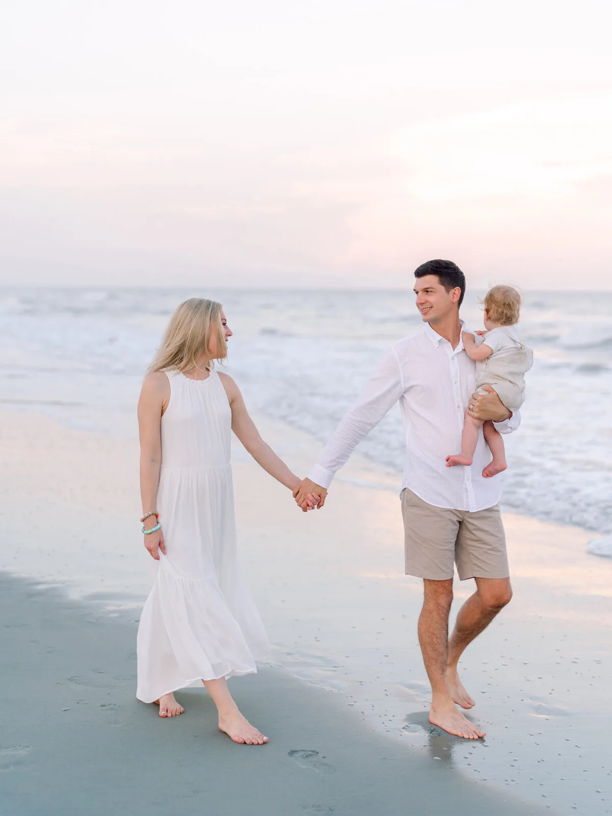 Couple holding hands with their baby on the beach in North Myrtle Beach