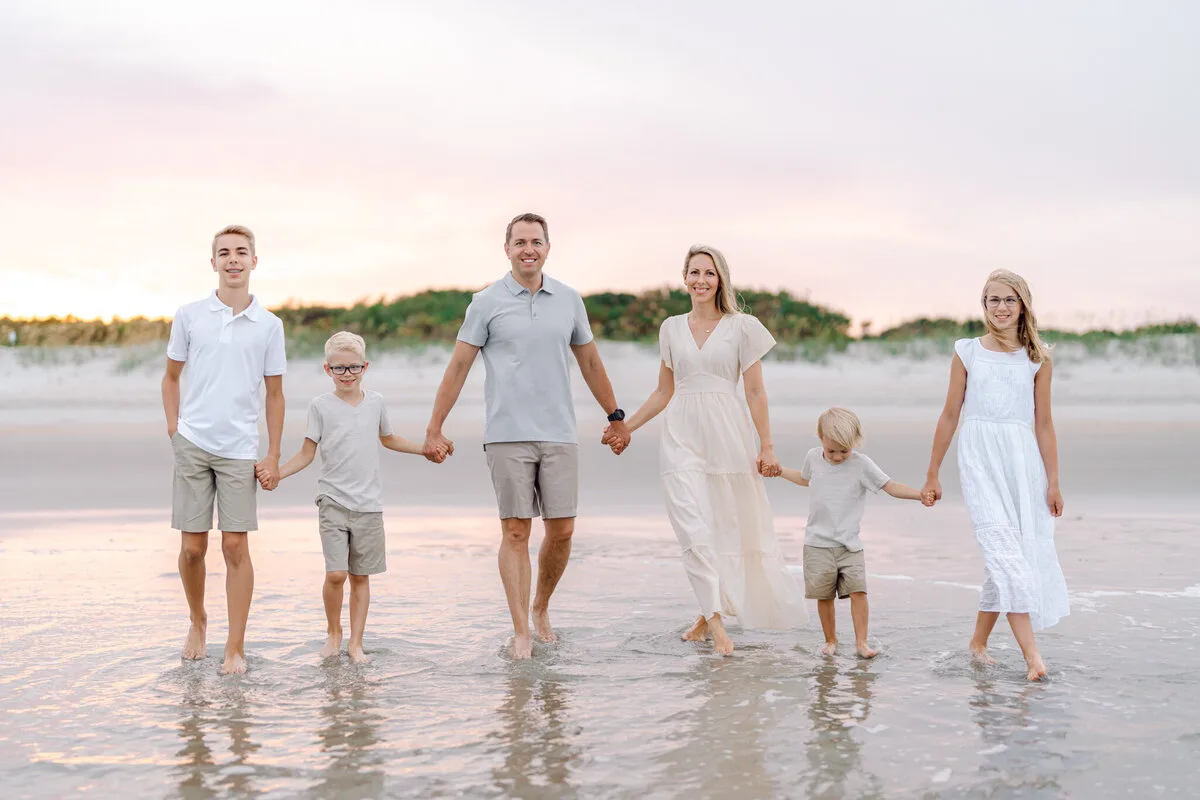 Family holding hands on the beach by the dunes in North Myrtle Beach
