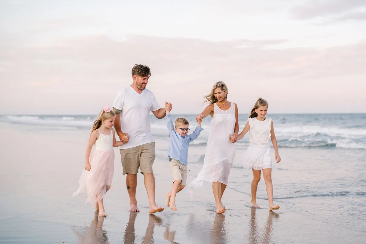 Family of six walking the shoreline at sunset in North Myrtle Beach