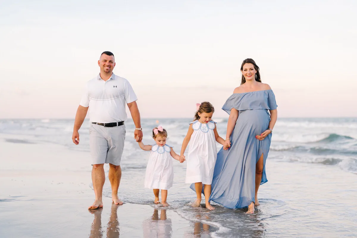 Family walking the shoreline in soft pastel light in North Myrtle Beach