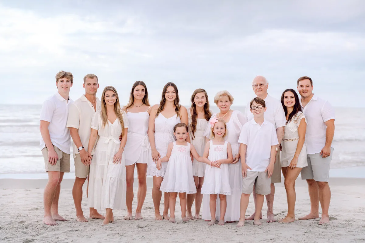 Large family in white standing together on the beach at sunset in North Myrtle Beach