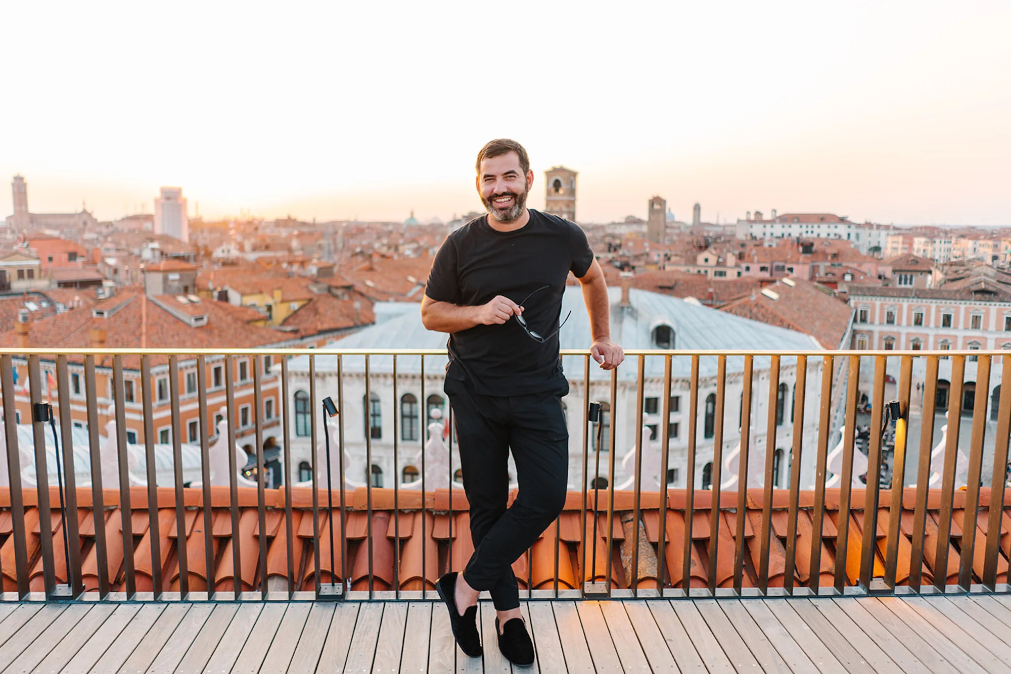 Pasha Belman, Myrtle Beach photographer and founder, smiling on a terrace above the rooftops of Venice, Italy