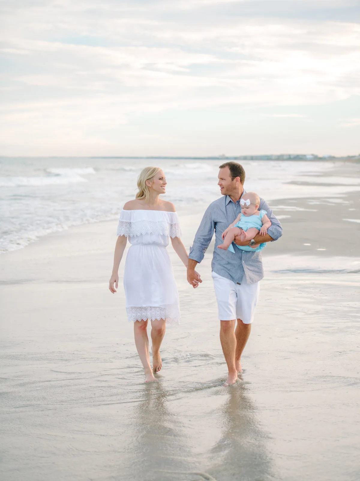 Couple with their baby walking in the surf at Pawleys Island beach