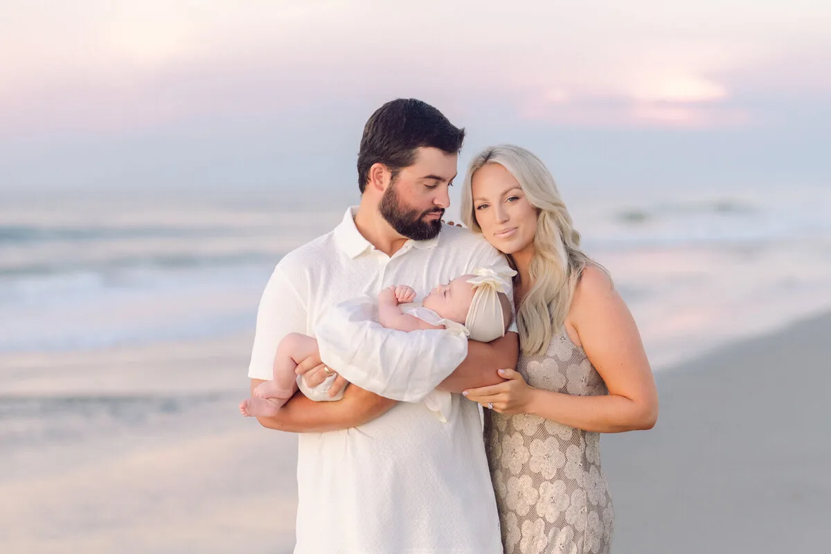 Couple with their newborn baby at sunrise in Pawleys Island