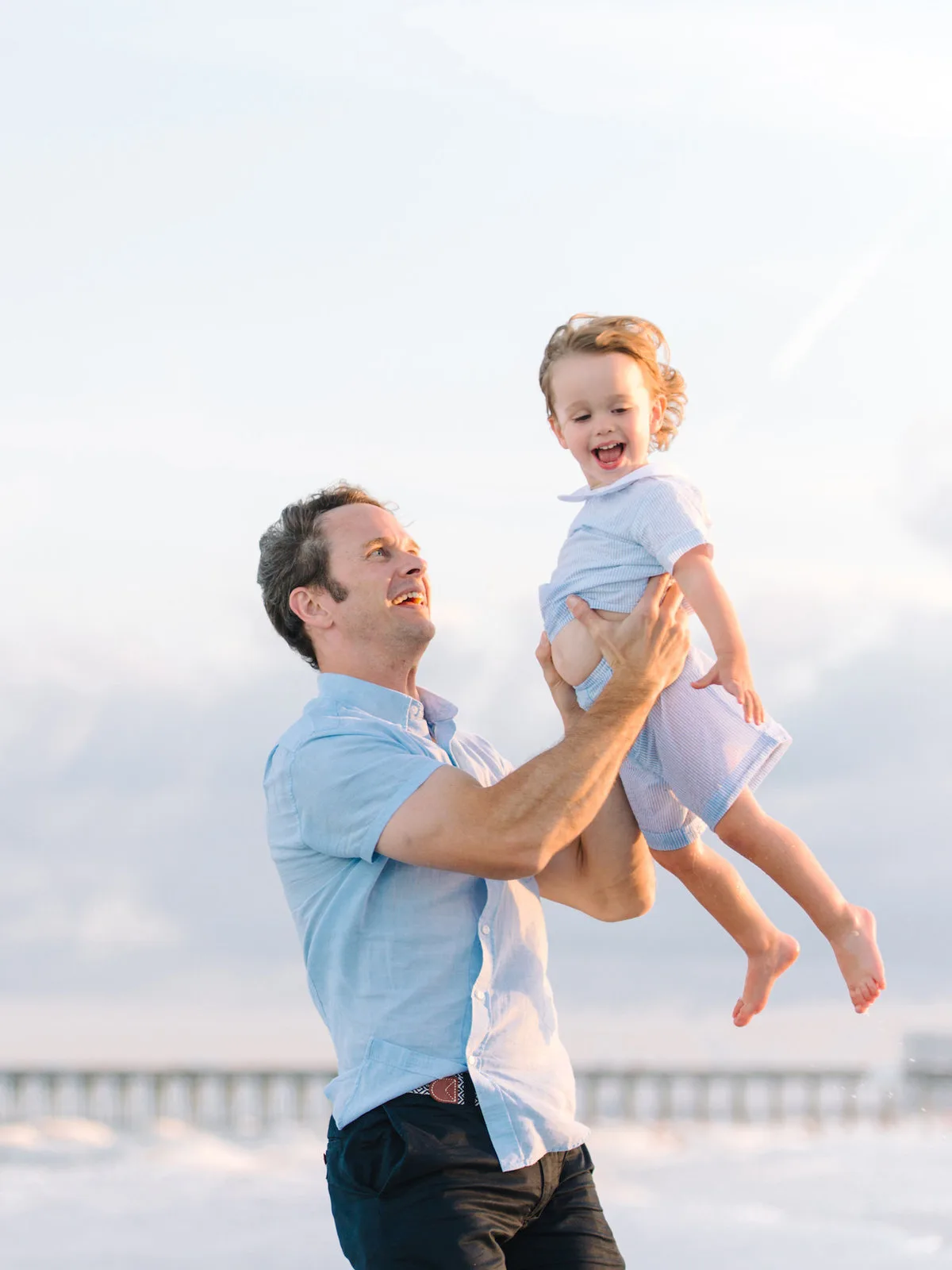 Dad lifting his son on the beach by the pier near Pawleys Island