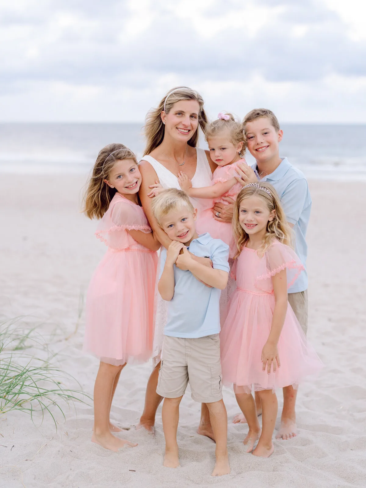 Family of six in pink and blue outfits on the beach in Pawleys Island