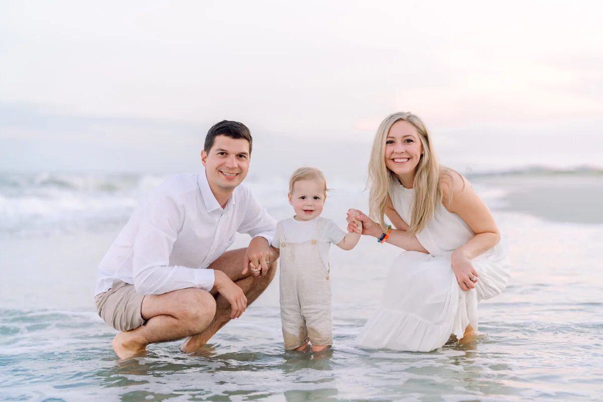 Parents playing with their toddler in the shallow water at Pawleys Island