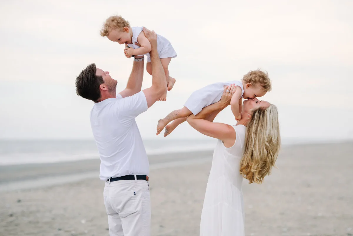 Parents swinging their child in the air on the beach in Pawleys Island
