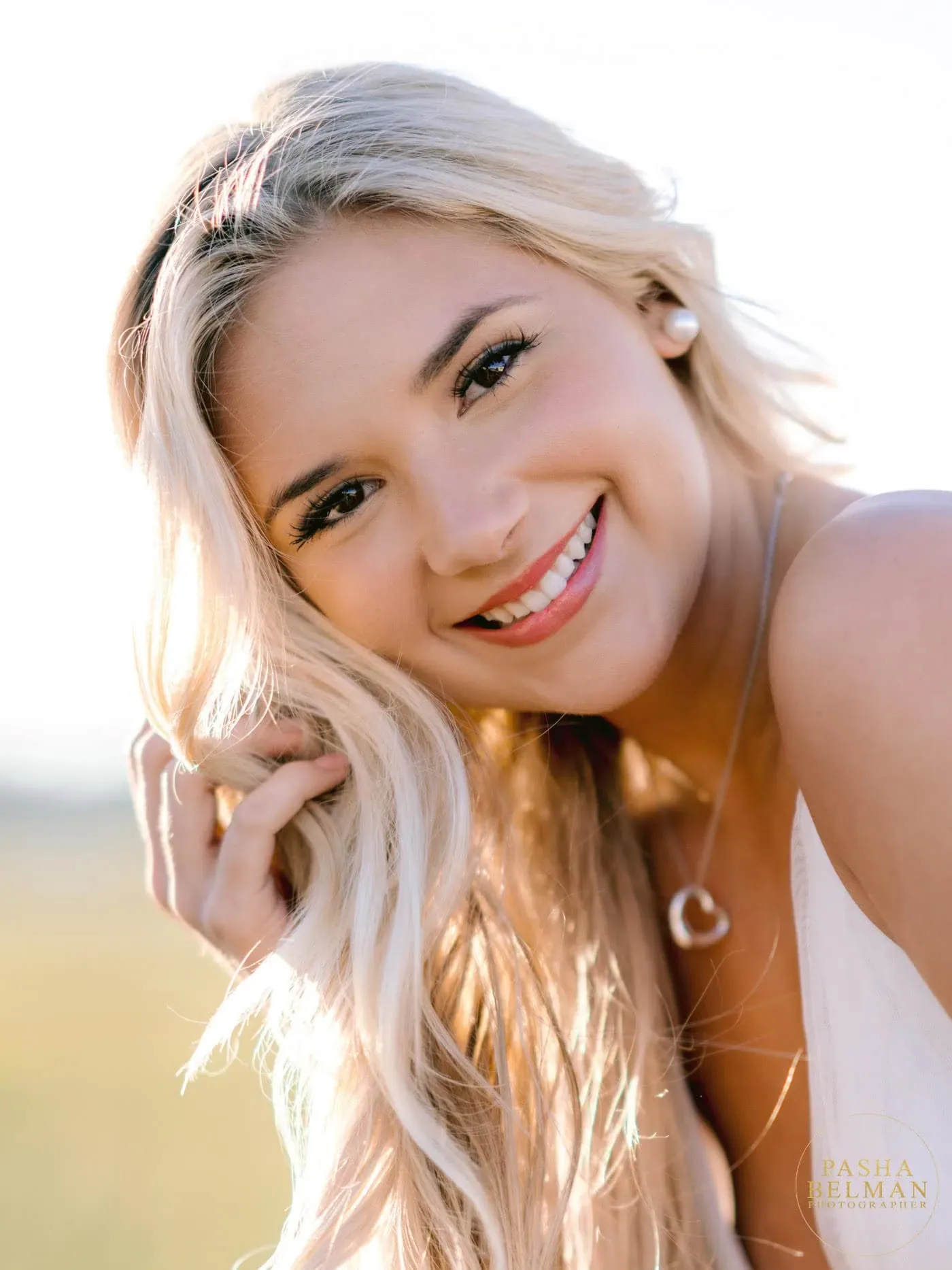 Close-up portrait of a smiling blonde high school senior in warm golden light by Pawleys Island senior photographer Pasha Belman