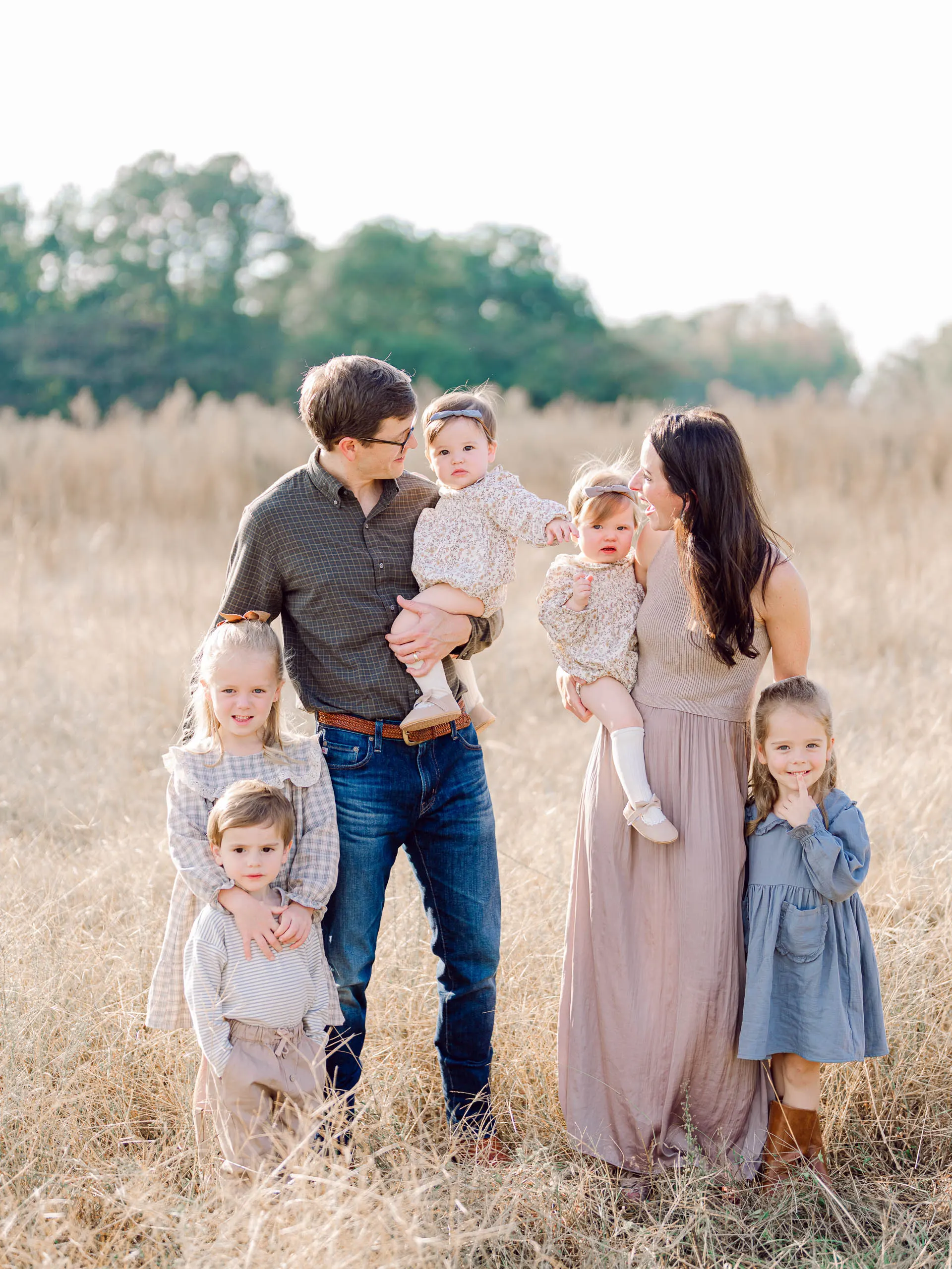 Mother and father with their five children standing close together in tall golden grass