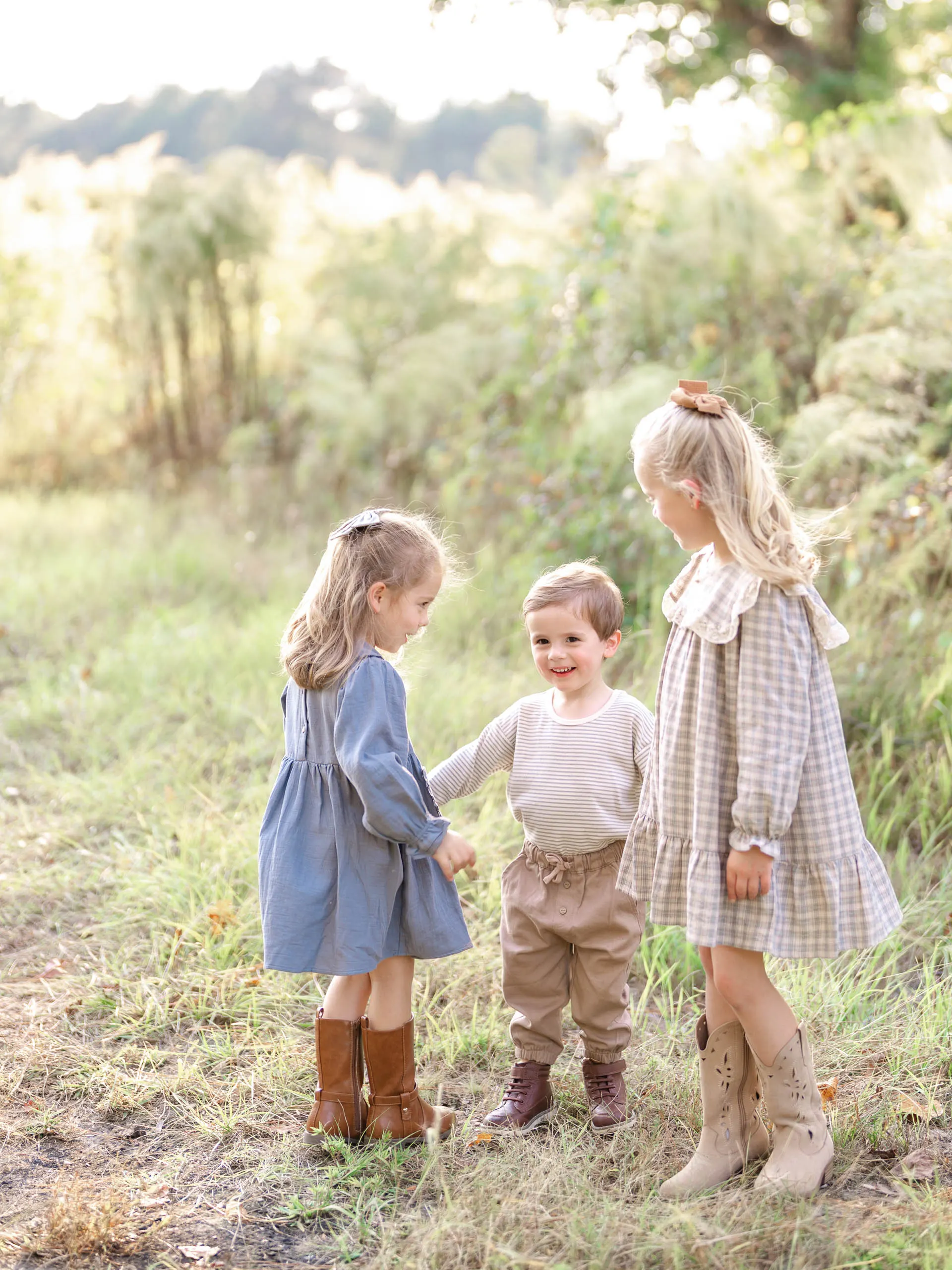 Three young children standing together in a green field in Pinehurst, North Carolina