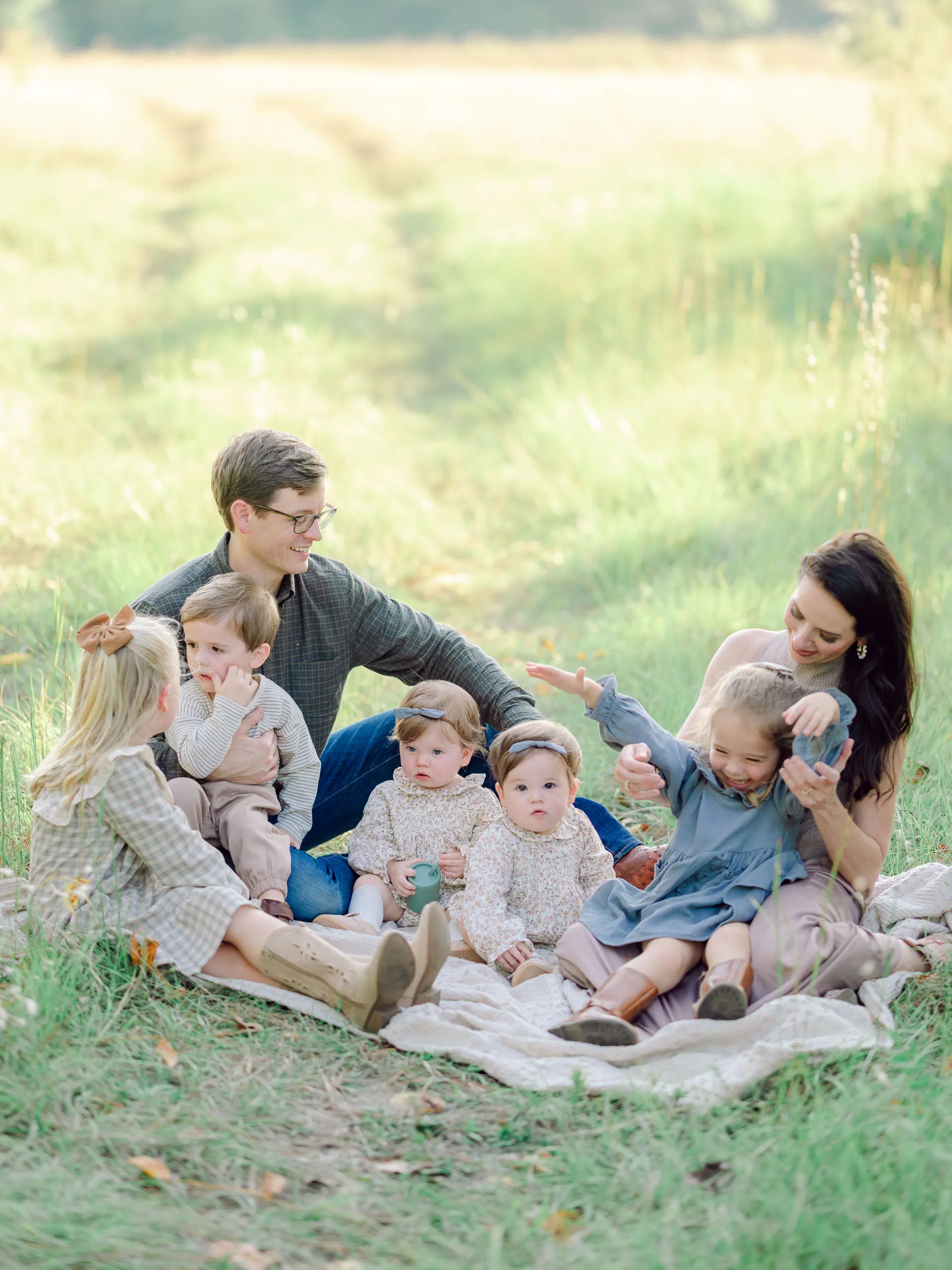 Family sitting together on a blanket in a green field during a Pinehurst NC family session