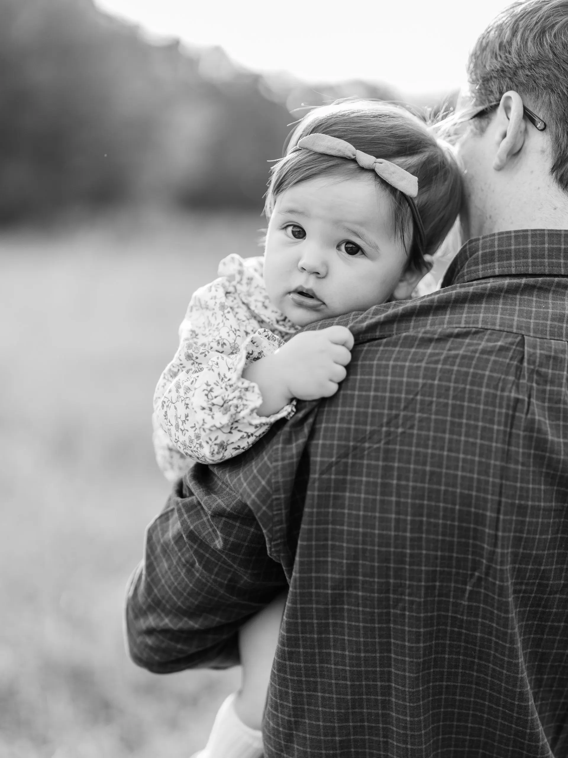 Black and white photo of a baby resting on her father’s shoulder